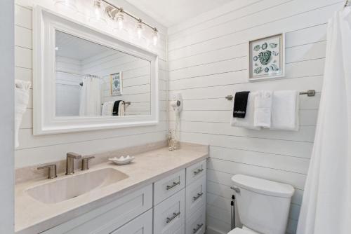 a white bathroom with a sink and a mirror at Beachcomber, Unit 302 in Demere Park