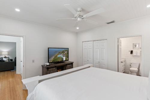 a white bedroom with a bed and a flat screen tv at Beachcomber, Unit 302 in Demere Park
