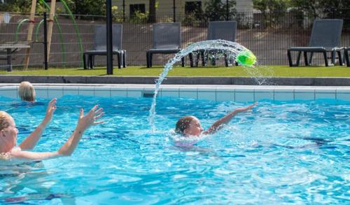 two girls playing with a ball in a swimming pool at Chalet Vakantie Wageningen Veluwe in Wageningen