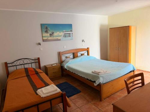 a bedroom with two beds and a table and a cabinet at Nefama Pensao in Ourique
