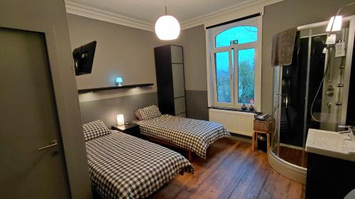 a room with two beds and a bathroom with a shower at B&B De Gastfabriek in Tielt