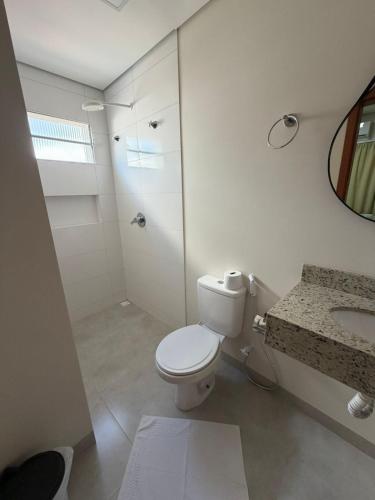 a white bathroom with a toilet and a sink at Hotel Colorado in Vilhena