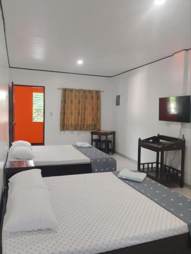 a room with four beds and a television and a desk at Tiza Manor Inn in Roxas City