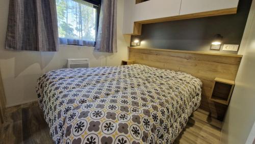 a bedroom with a bed with a blue and white comforter at Les Prairies de la Mer - Baie de Somme in Favières