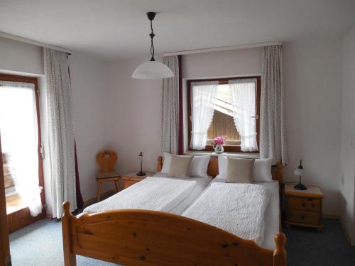 a bedroom with a bed with white sheets and windows at Schmidhauser Hof in Unterwössen