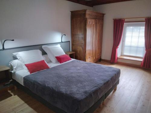a bedroom with a large bed with two red pillows at L'amandier in Thouars