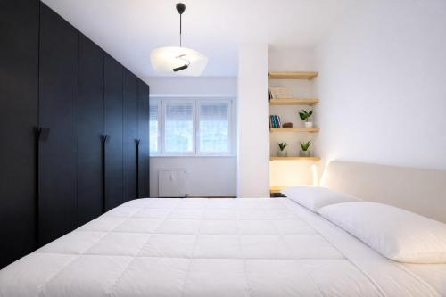 a bedroom with a white bed and black cabinets at Bella Vita Stays Happy in Sondrio