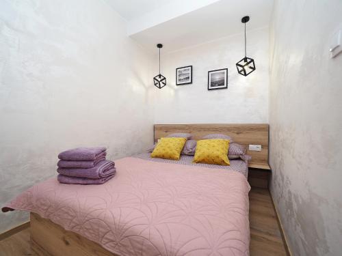 a bedroom with a bed with pink sheets and yellow pillows at Apartament KLARA in Sarbinowo