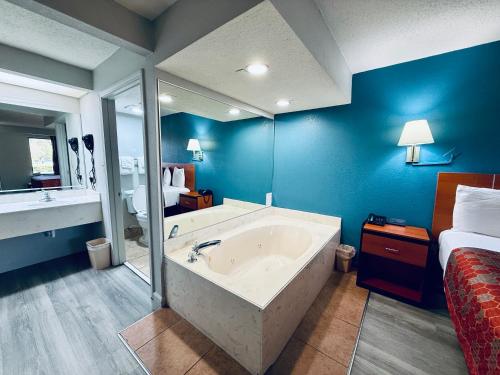 a large bathroom with a tub and a bed at Luxury Inn & Suites in Selma