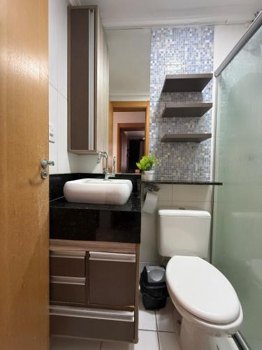 a bathroom with a white toilet and a sink at Apartamento próximo Aeroporto Cuiabá in Várzea Grande