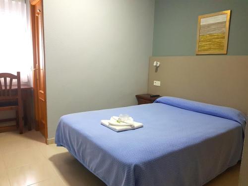 a bedroom with a blue bed with towels on it at Hostal Soto in La Virgen del Camino