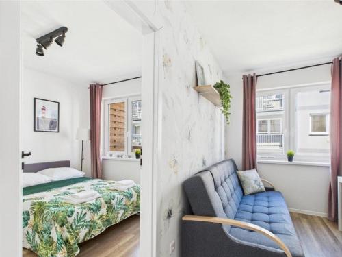 a bedroom with a bed and a blue couch at Apartament 44A Dębina I 400 m do plażyl przyjazny rowerzystom in Debina