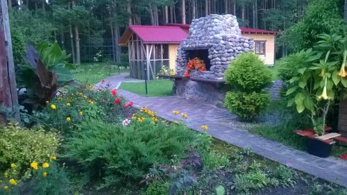 a garden with a stone fireplace and a small house at Oāze Smiltenē in Smiltene