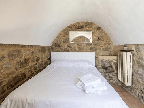 a bedroom with a white bed with a stone wall at DaVilla Sanremo - Entire Villa, Sea View & Pool in Pampara