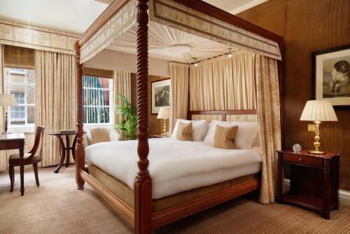 a bedroom with a canopy bed and a desk at Rubens At The Palace in London