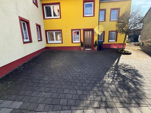 a yellow and red building with a driveway at Das kleine Vulkanhaus in Daun