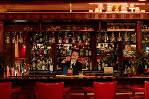 a man sitting at a bar with a drink at Rubens At The Palace in London