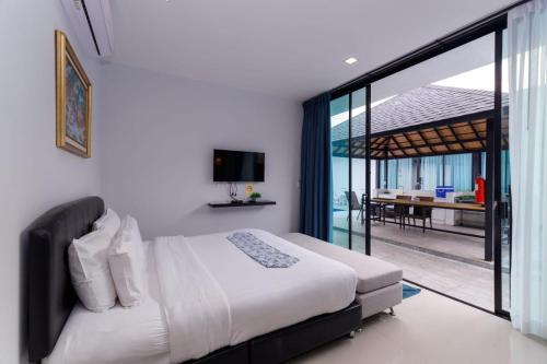 a bedroom with a large bed and a balcony at Lespalm Resort by Vacayandco in Ban Thalat Choeng Thale