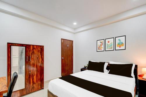 a bedroom with a white bed and a wooden door at Super Townhouse Nallagandla Nest in Hyderabad