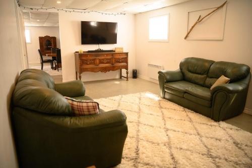 a living room with two leather couches and a television at Lower Floor - Mont-Video in Barraute