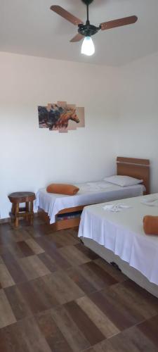 a bedroom with two beds and a ceiling fan at Pousada Xodó in São Pedro