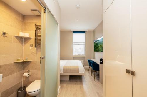 a small bathroom with a toilet and a bed at NOX Kensington in London