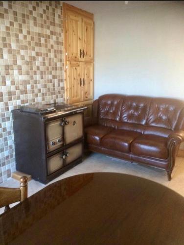 a living room with a leather couch and a stove at Kathleen’s Haven in Causeway