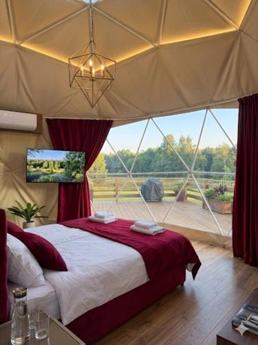 a bedroom with a bed and a large window at Glamping LA BELLA Suntago in Aleksandria