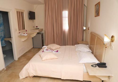 a bedroom with a large white bed with pillows at Appart Hotel Rodes in Mezraya