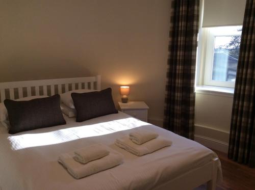 a bedroom with a bed with two towels on it at Craig Cottage in Banff
