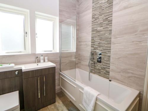 a bathroom with a tub and a shower and a sink at Lumsdale in Matlock
