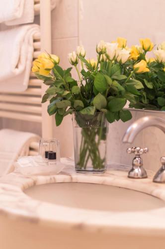 a vase of yellow flowers sitting on a bathroom sink at Hotel Polo in Rimini