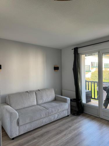 a living room with a couch and a sliding glass door at Studio dans résidence avec piscine in Bidart