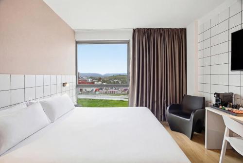 a hotel room with a bed and a chair and a window at B&B HOTEL Miranda de Ebro in Rivabellosa