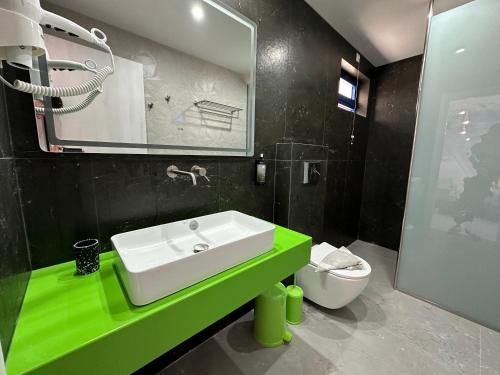 a bathroom with a green sink and a toilet at Bouradanis Art Hotel in Marmari