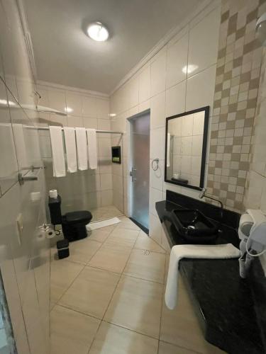a bathroom with a sink and a toilet and a mirror at Pousada Sol e Cia Tur in Caraguatatuba