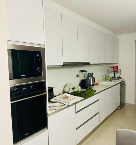 a kitchen with white cabinets and a black appliance at Principality Apartment in Cardiff