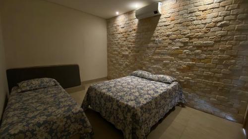 a room with two beds and a brick wall at Recanto das Palmeiras hidro in Hidrolândia
