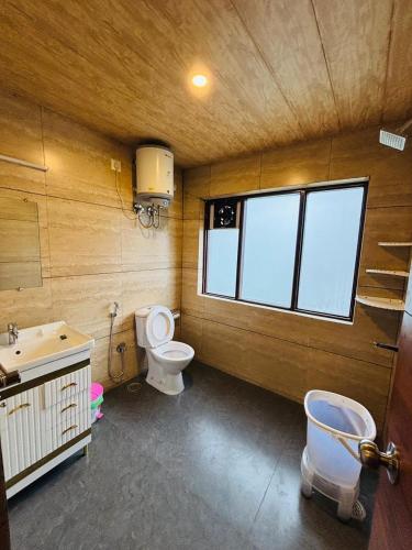 a bathroom with a toilet and a sink and a window at Sati Heights in Vashisht