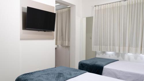 a hotel room with two beds and a flat screen tv at Nostro Hotel in Pato Branco