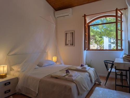 a white bedroom with a bed and a window at Villa Punta in Maslinica