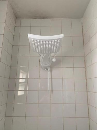 a white tiled bathroom with a basket on the wall at PRAIA DO MORRO NA QUADRA DO MAR com 2 Quartos sendo 1 Suíte mais Kit Praia e ao lado PRAIA CENTER in Guarapari