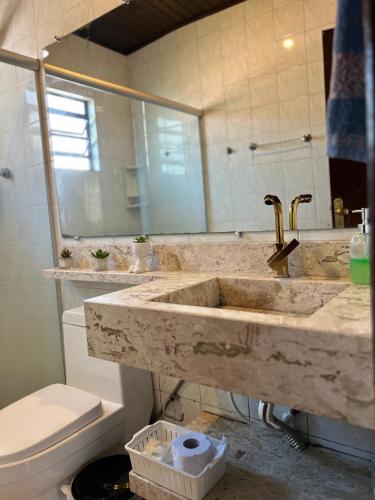 a bathroom with a sink and a toilet at Casa com piscina aquecida e quadra de vôlei in Osório