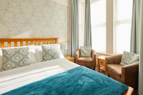 a bedroom with a bed and a chair and windows at The Tennyson in Bridlington