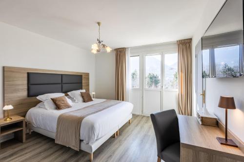 a bedroom with a bed and a desk and a chair at Hotel Vauban Briançon Serre Chevalier in Briançon