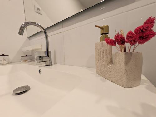 a bathroom sink with a vase with flowers in it at Yutz and Zen in Basse-Yutz