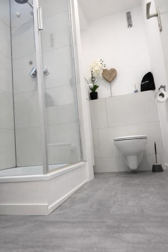 a white bathroom with a shower and a toilet at Black & Yellow Studio in Augsburg
