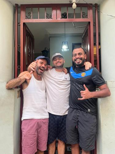 three men posing for a picture in a doorway at Books Hostel in Rio de Janeiro