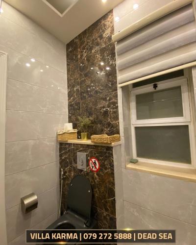 a bathroom with a toilet and a window at Villa karma in Al Rama