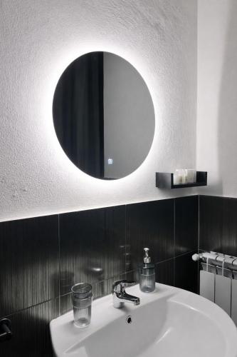 a bathroom with a sink and a round mirror at Atenè Rooms in Agrigento
